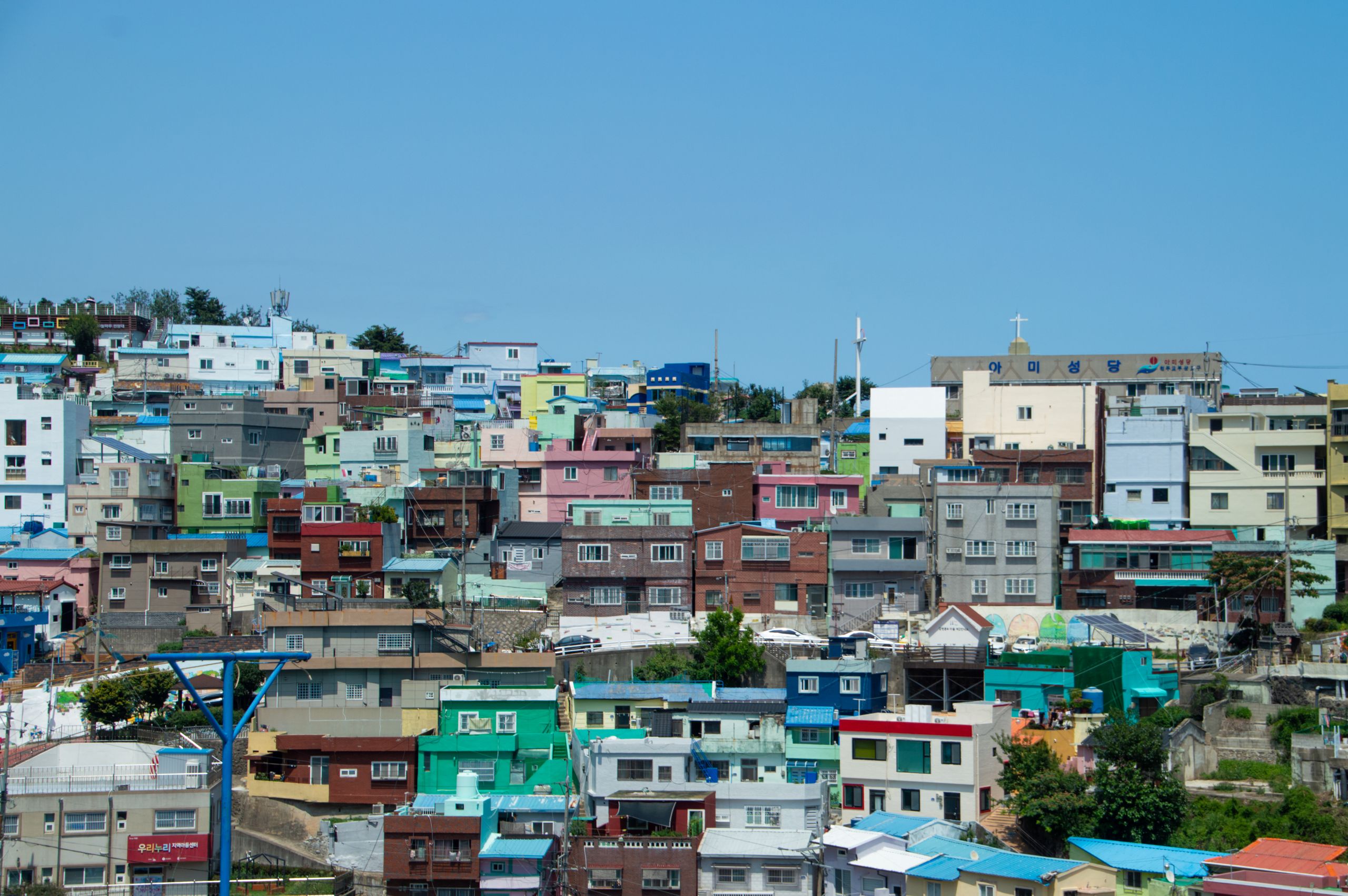 Vibrant hillside neighborhood in Busan displaying colorful houses under a clear blue sky.